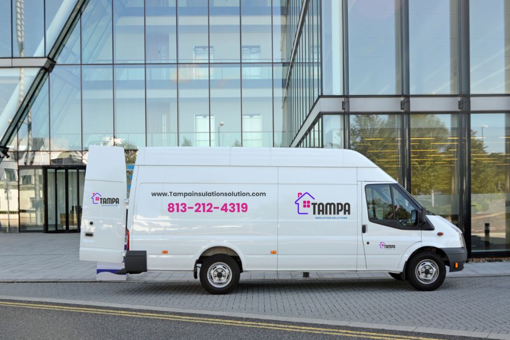 White delivery van parked outside a modern glass building, featuring "TAMPA" and contact information on its side.