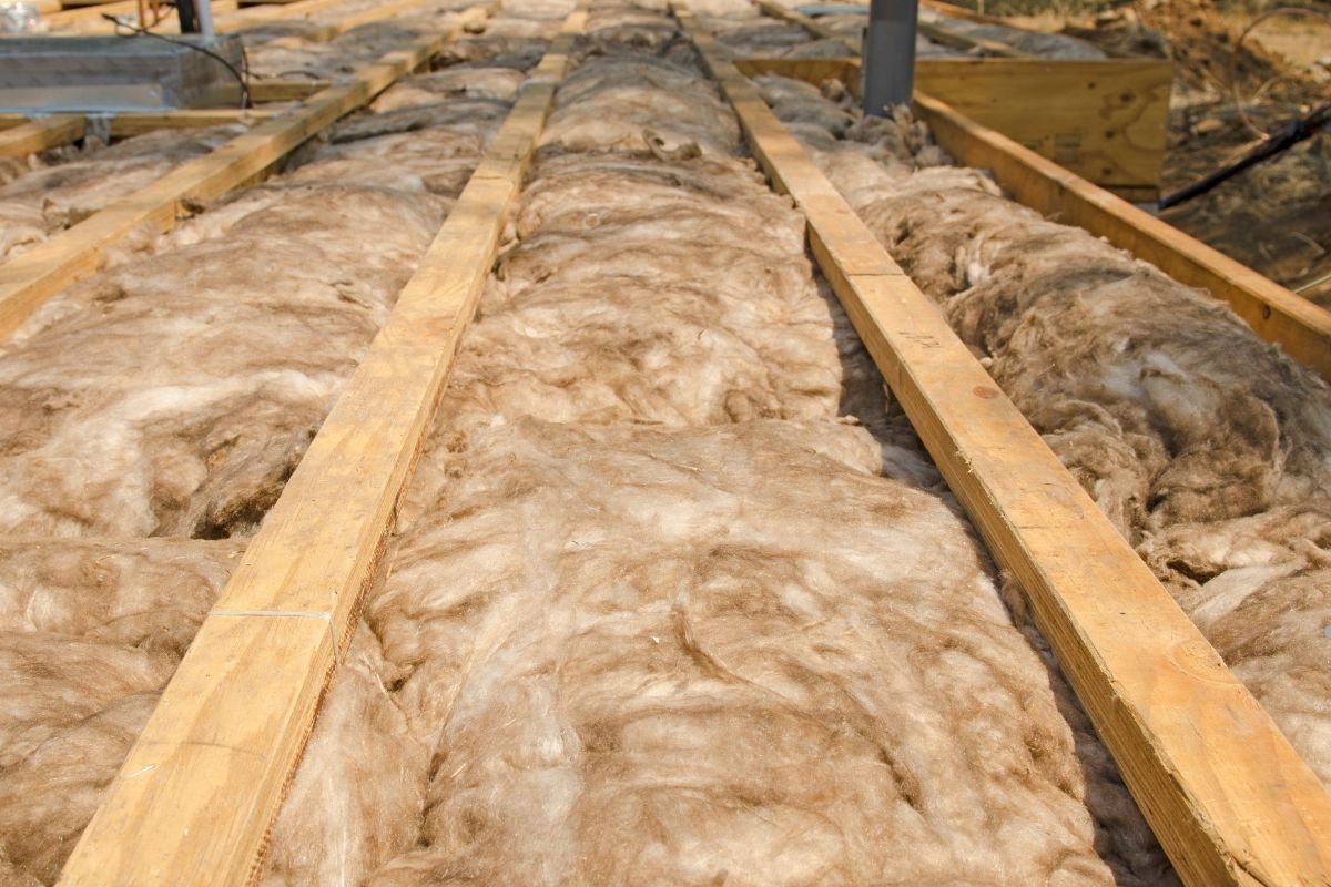 A pile of insulation material on a wooden floor, indicating preparation for an insulation installation service.