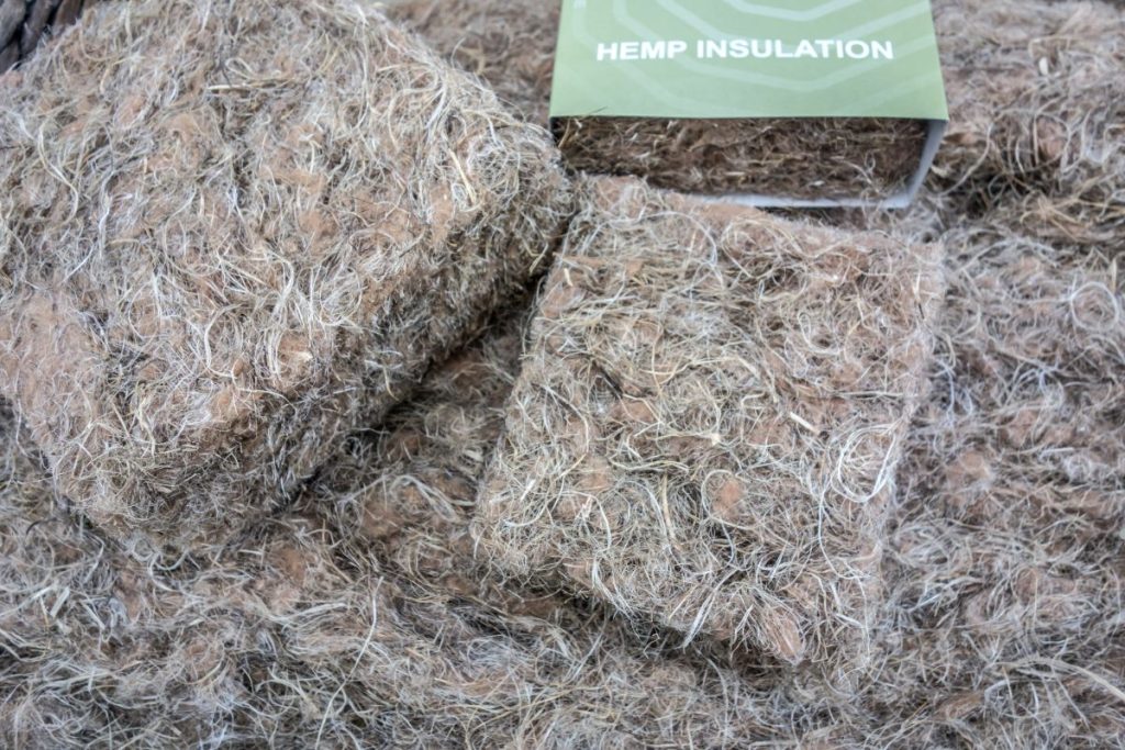 A pile of hay with a sign reading "Hemp Insulation" promoting eco-friendly insulation services.